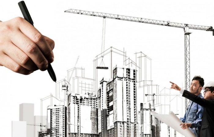 Architects planning a construction project, with a large hand sketching building designs in the background, representing collaboration and architectural design.